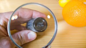 person checking expiry dates of makeup product using magnifying glass
