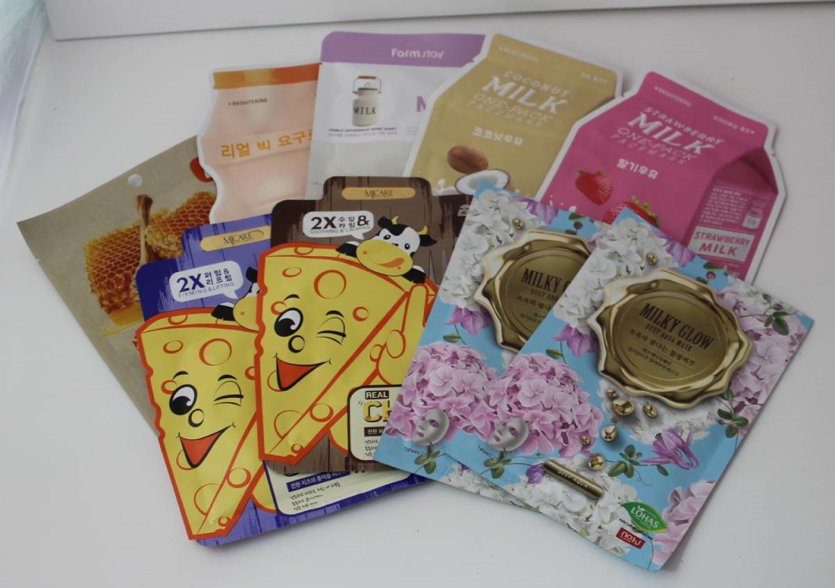 A collection of various face masks, including flavors like honey, milk, and strawberry, with playful designs and vibrant packaging.