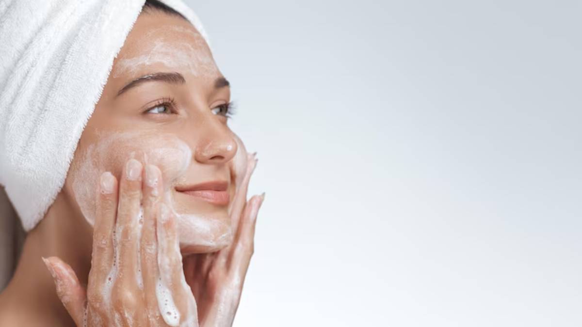 A person lathers their hands with a cleansing foam, showcasing a skincare routine in a serene, softly lit environment.