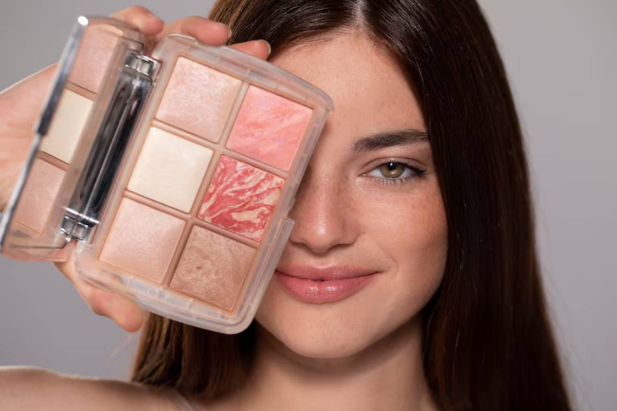 A person holds a compact makeup palette with six shades, displaying warm tones in a clean studio setting.