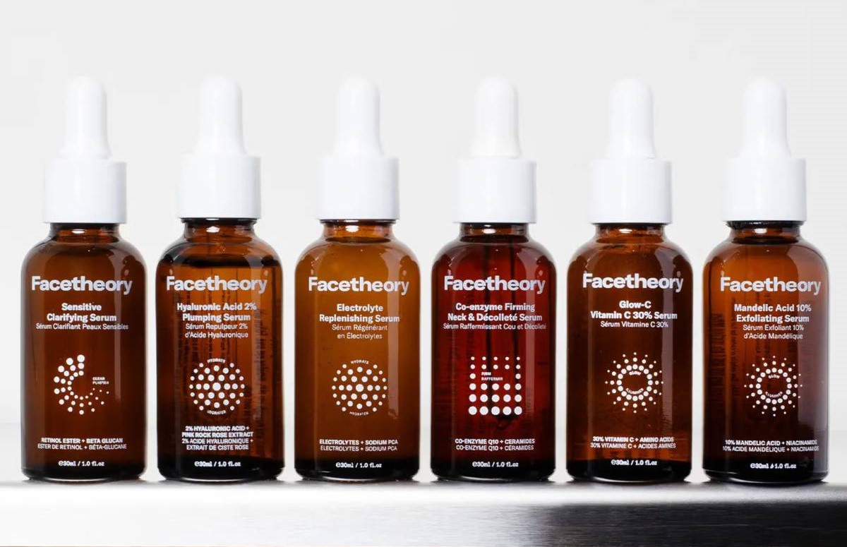 A lineup of six Facetheory serum bottles on a gray background, showcasing various skincare formulations for hydration and exfoliation.