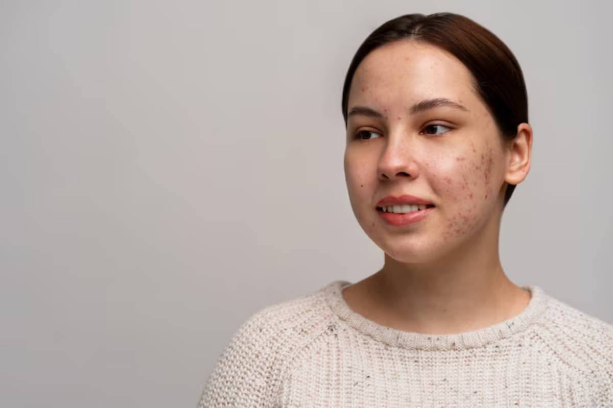 A woman in a knitted sweater poses against a soft, neutral background, conveying a calm and composed expression.