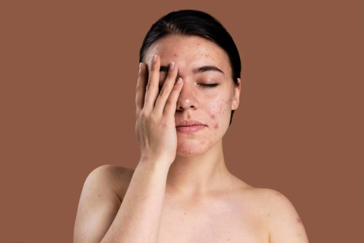 A person with dark hair holds their hand to their face, against a warm brown background, showcasing a contemplative pose.