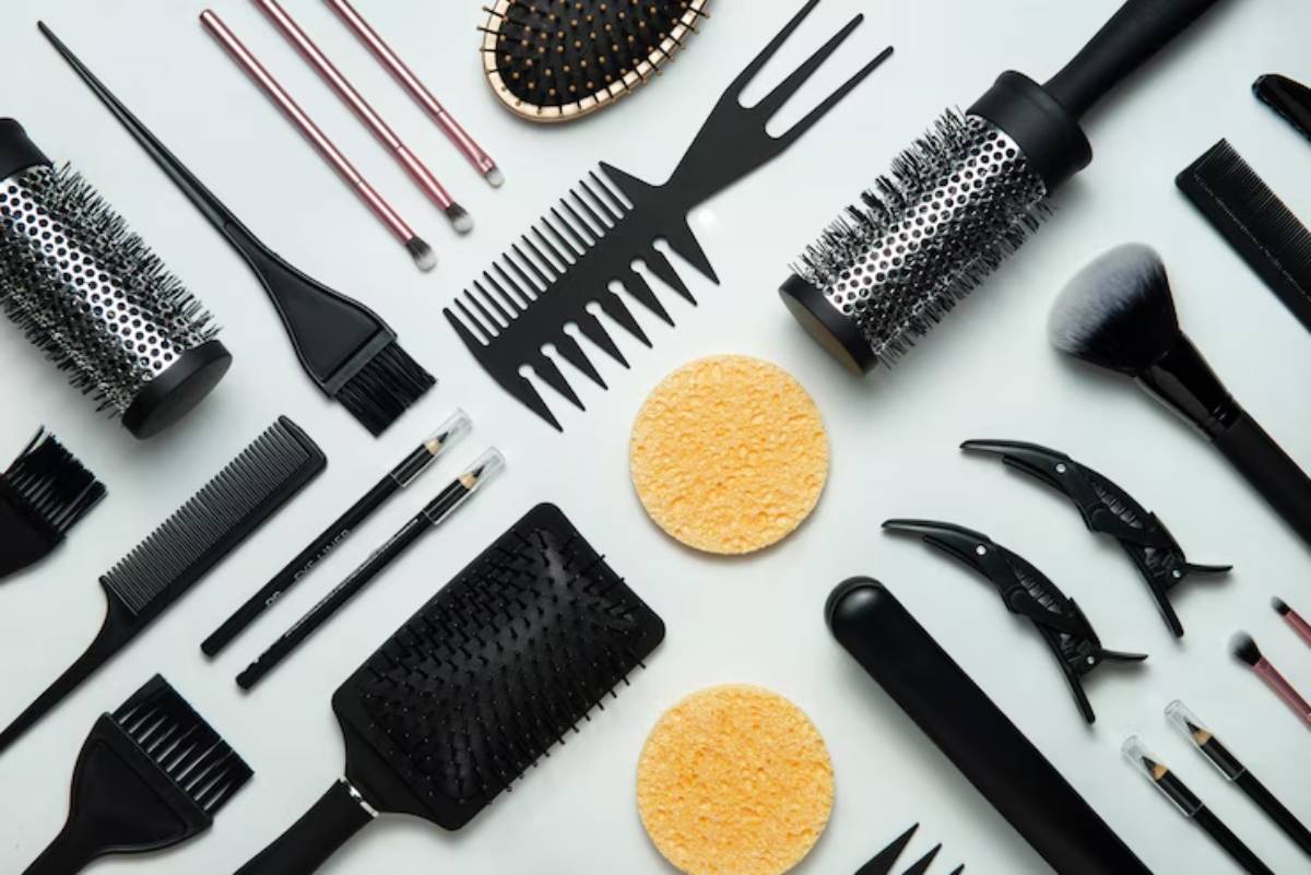 An assortment of hair styling tools including brushes, combs, sponges, and clips organized on a white background.