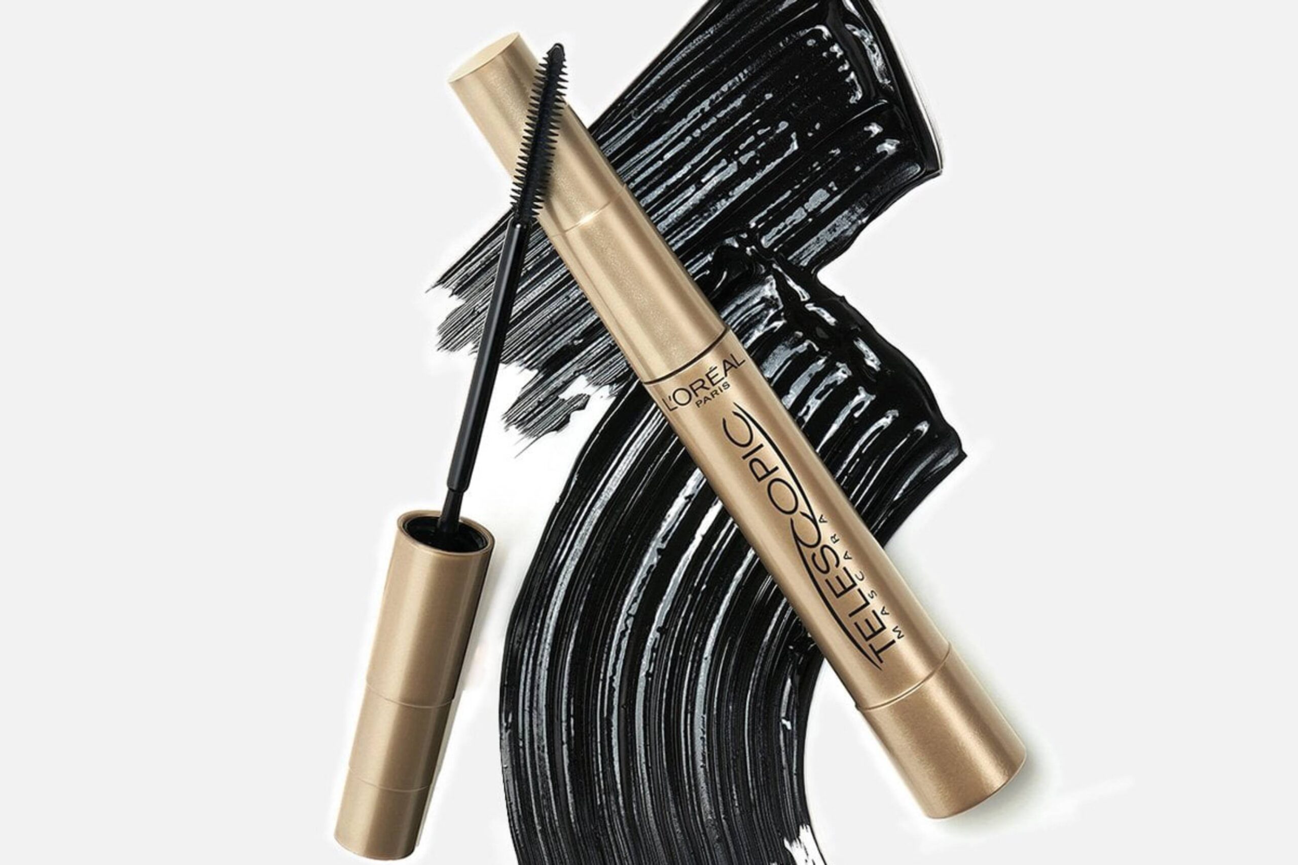 Golden tube of L'Oréal Telescopic mascara beside a black brush on a bold black mascara streak background.