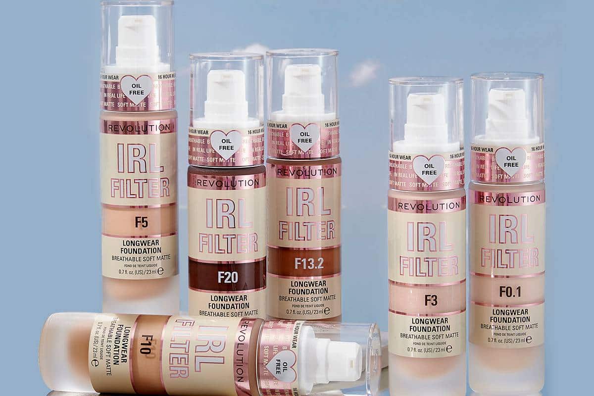 Seven transparent pumps of Revolution IRL Filter Longwear Foundation in various shades, labeled for oil-free, breathable, soft matte finish.