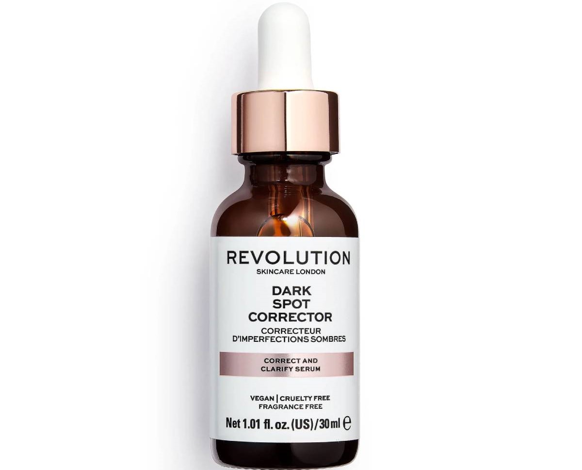 A bottle of Revolution Skincare Dark Spot Corrector serum, featuring a white label, a dropper cap, and a brown glass design.