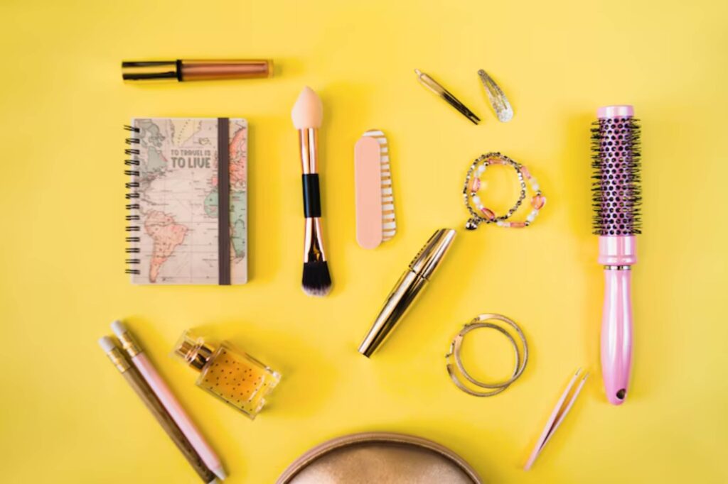 Flat lay of beauty and travel items on a bright yellow background: cosmetics, a map notebook, jewelry, and tools.