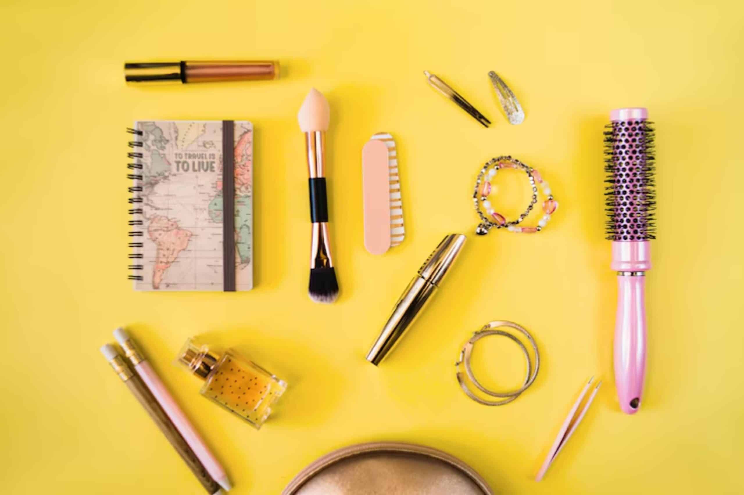 Flat lay of beauty and travel items on a bright yellow background: cosmetics, a map notebook, jewelry, and tools.