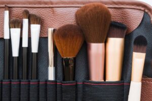 A variety of makeup brushes displayed neatly in a black and brown organizer, showcasing different sizes and shapes for diverse applications.
